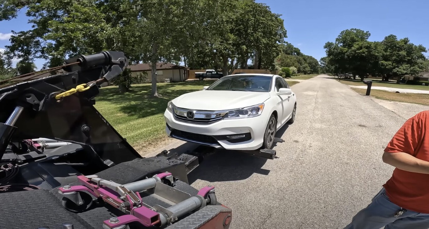 Roadside assistance tow truck hooking up a Honda Accord on a suburban road